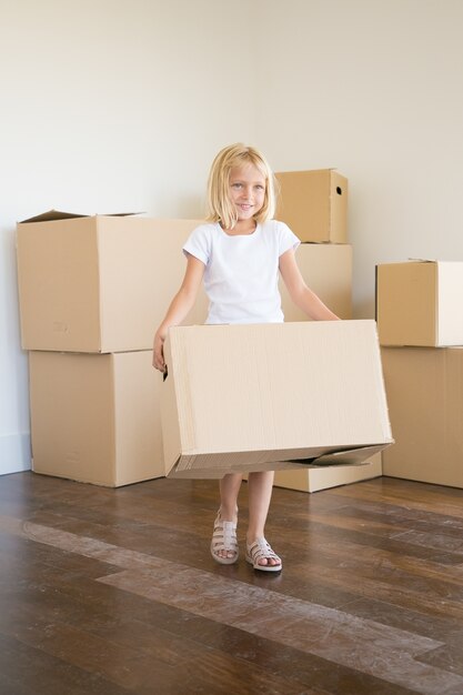 Caucasian little girl carrying cardboard box during removal