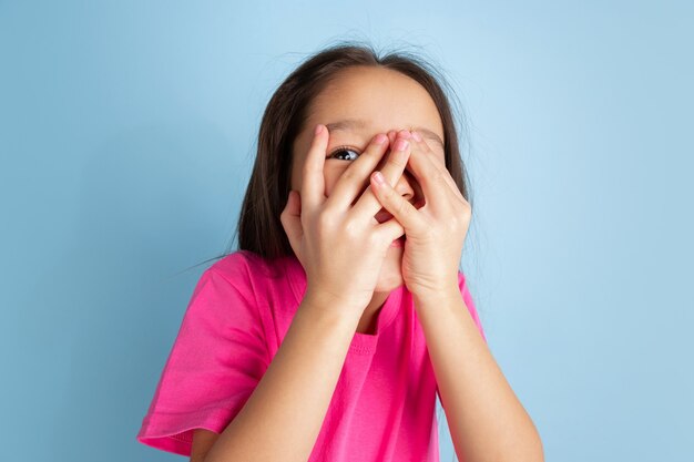 Caucasian little girls portrait on blue studio wall