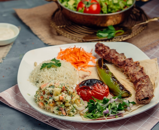 Кавказский люле кебаб с овощным салатом, жареными помидорами, перцем, зеленью и рисом.