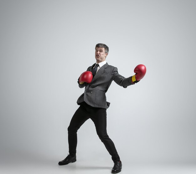 Caucasian man in office clothes boxing isolated on grey  wall