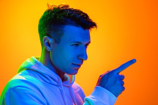 Caucasian man's portrait isolated on yellow background in mixed neon light. Handsome male model.