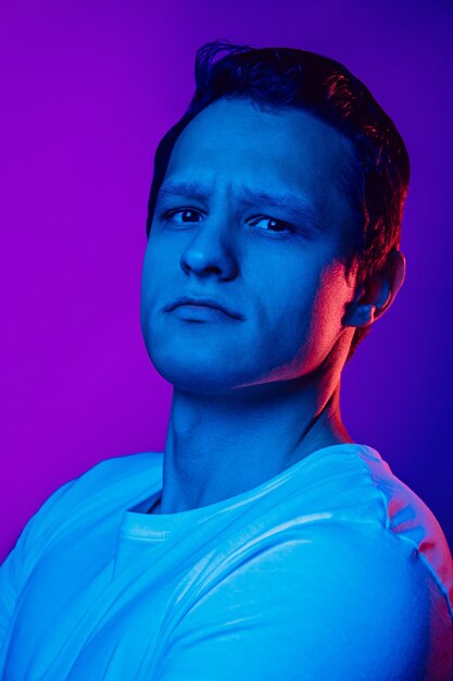 Caucasian man's portrait on purple blue  background in multicolored neon light.