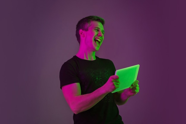 Caucasian man's portrait on purple studio in neon light