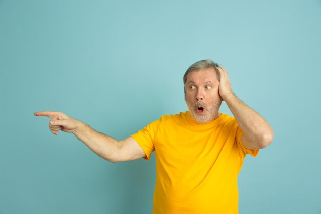 Caucasian man shocked pointing at side isolated on blue