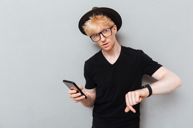 Caucasian man using his watch and mobile phone.