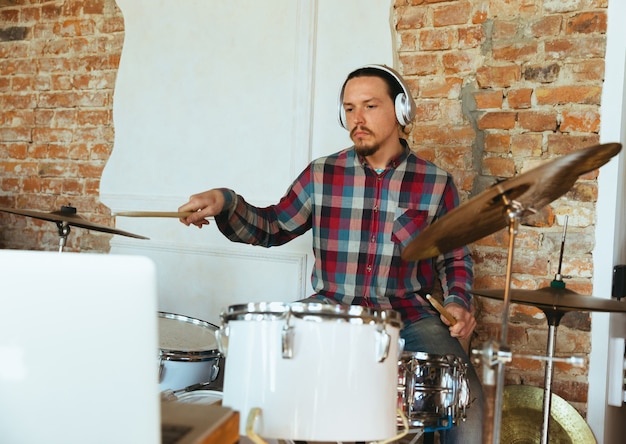 Free photo caucasian musician playing drumms during online concert at home isolated and quarantined.