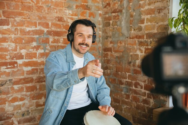 Caucasian musician playing hand drum during online concert at home