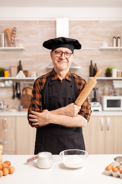 Бесплатное фото Кавказский старик в фартуке на домашней кухне улыбается