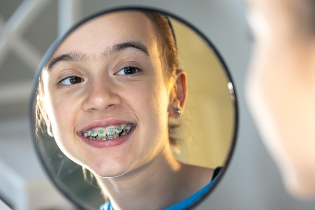 Caucasian preteen girl with braces on her teeth looking at the mirror