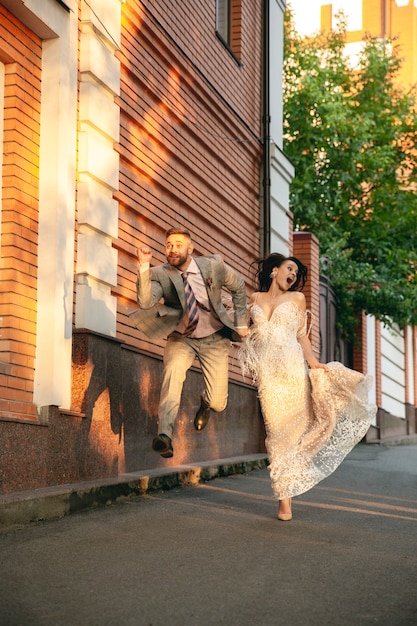 Caucasian romantic young couple celebrating marriage in city. Tender bride and groom on modern city's street. Family, relation, love concept