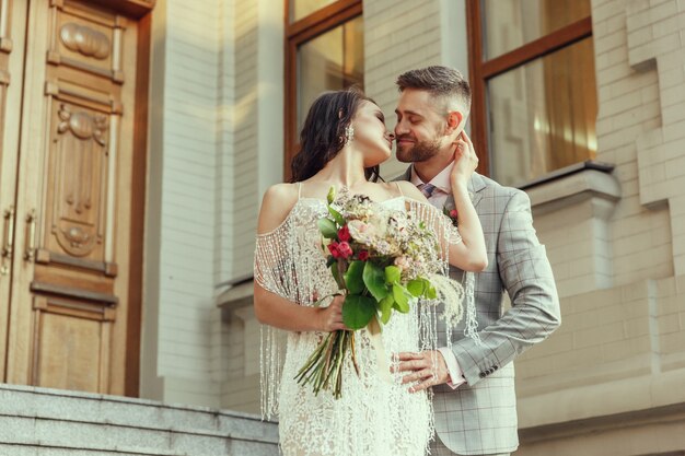 都市での結婚を祝う白人のロマンチックな若いカップル。近代的な街の通りで優しい新郎新婦。家族、関係、愛の概念