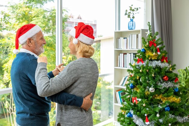 Caucasian senior couple elderly man and woman dancing together in living room with Christmas tree in background