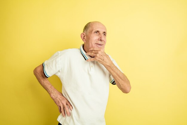 Caucasian senior man's portrait isolated on yellow studio