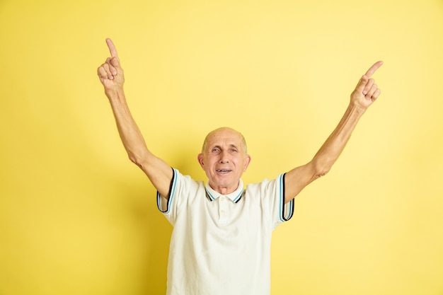 Caucasian senior man's portrait isolated on yellow studio