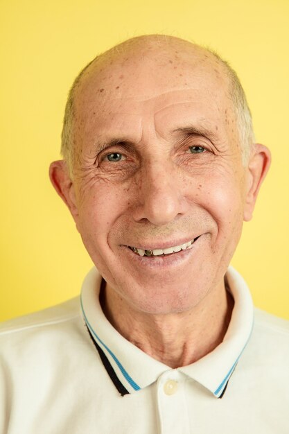 Caucasian senior man's portrait isolated on yellow studio