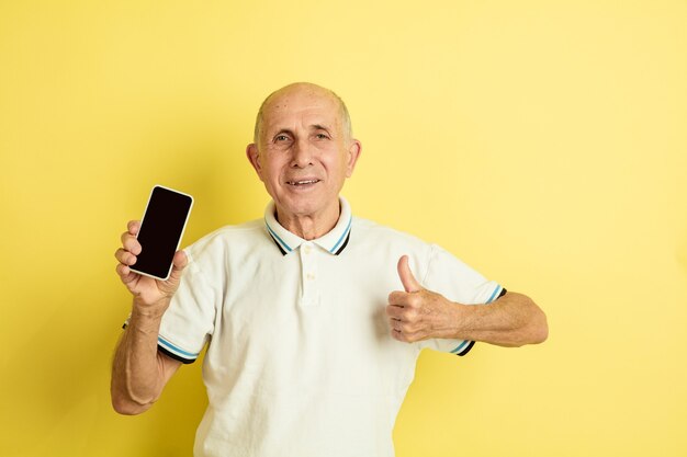 Caucasian senior man's portrait isolated on yellow wall