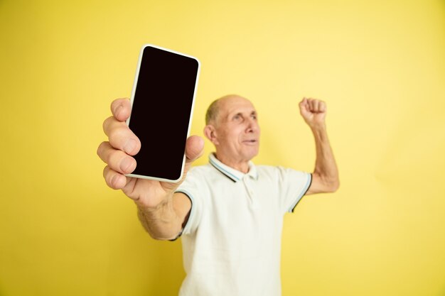 Caucasian senior man's portrait isolated on yellow