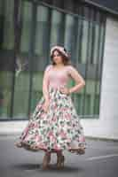 Free photo caucasian standing in front of a modern building in a pink dress and hairband