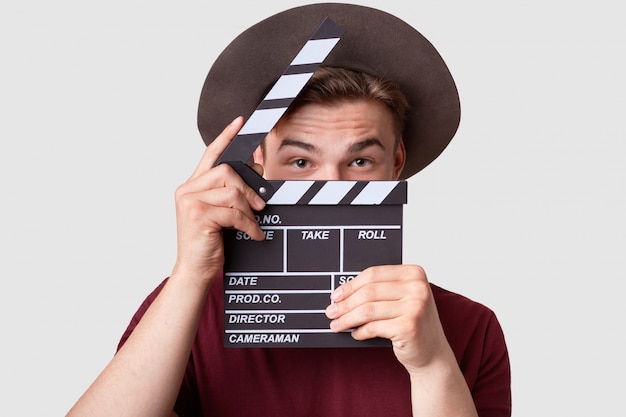 Free photo caucasian successful male producer looks through opened clapperboard