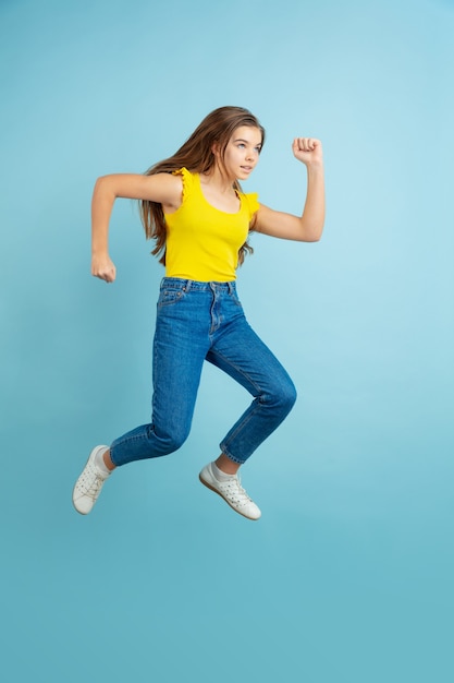 Caucasian teen girl portrait isolated on blue studio wall