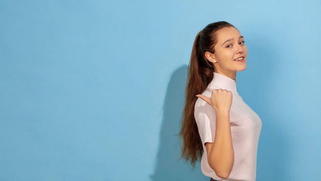 Caucasian teen girl portrait isolated on blue studio