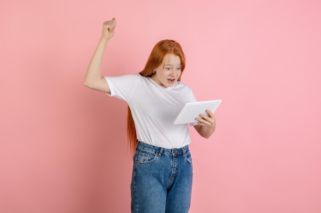 Caucasian teen girl's portrait isolated on coral pink studio background.