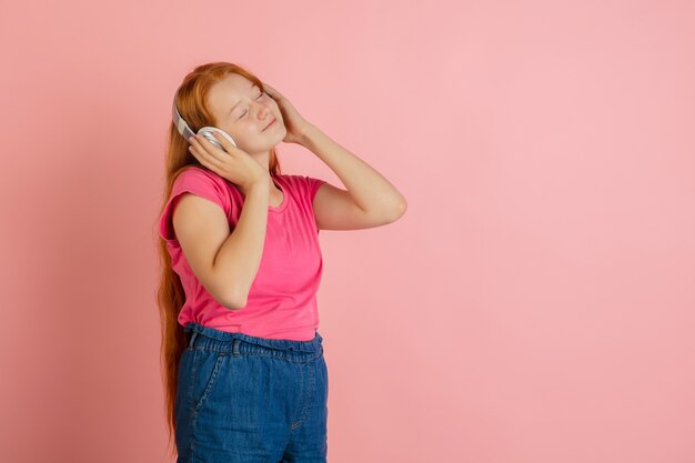 Caucasian teen girl's portrait isolated on coral pink studio