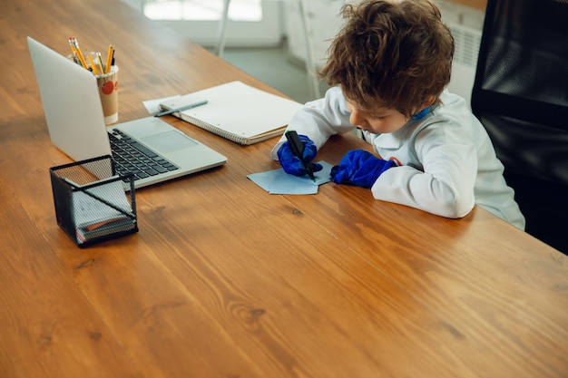 Free photo caucasian teenboy as a doctor consulting for patient, giving recommendation, treating. little doctor during prescriptioning drugs for patient. concept of childhood, human emotions, health, medicine.