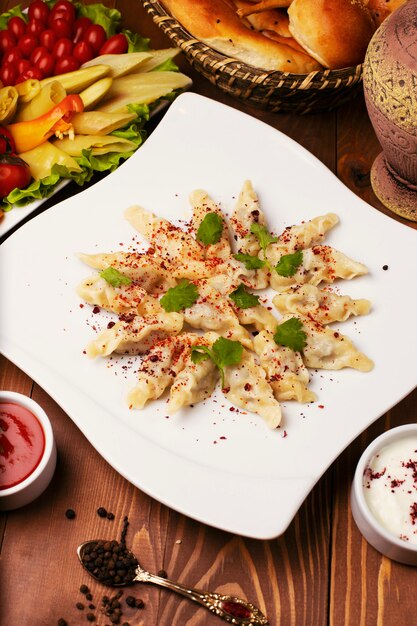 백인 전통 foodl dushbere, 거즈는 요구르트와 토마토 소스와 함께 제공됩니다. 흰 접시에 나무 테이블에 turshu로 장식