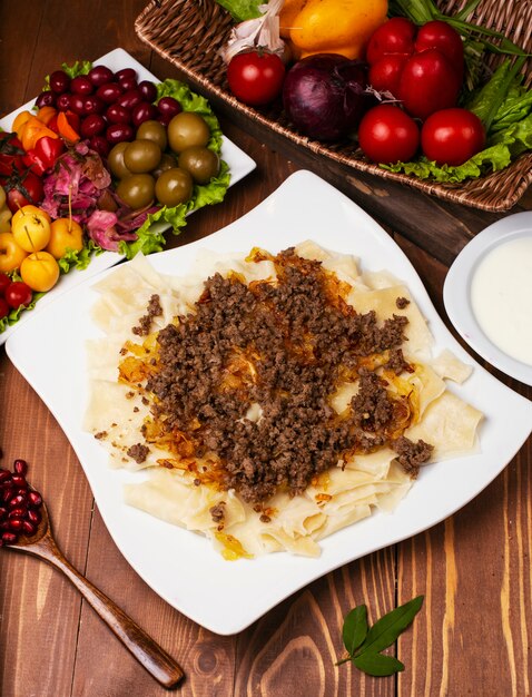 Caucasian traditional foor khingal, khinkali. Caucasian pasta with meat in white plate on wooden table.