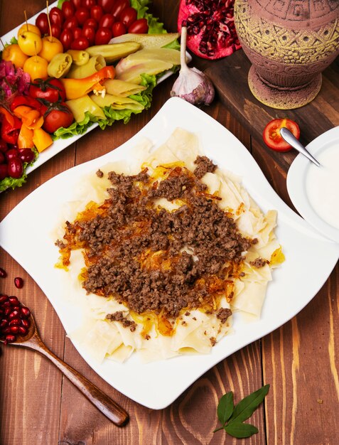 Caucasian traditional foor khingal, khinkali. Caucasian pasta with meat in white plate on wooden table.