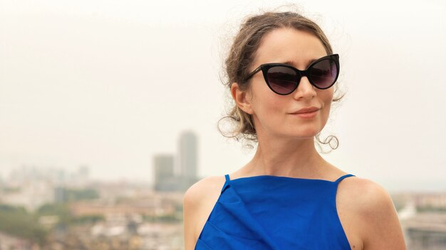 背景、スペイン、バルセロナの景色を望む青いドレスを着た白人女性