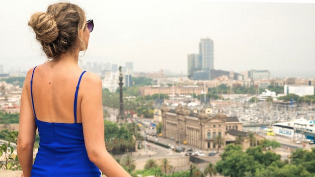 Foto gratuita donna caucasica in abito blu con vista sullo sfondo di barcellona, spagna