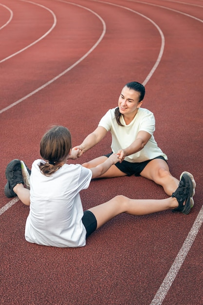 Free photo caucasian woman and little girl are engaged in fitness at the stadium