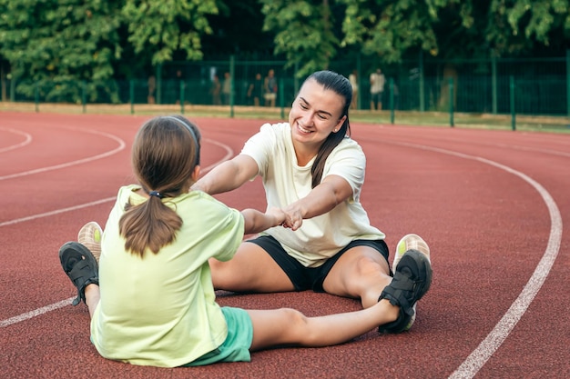 Free photo caucasian woman and little girl are engaged in fitness at the stadium