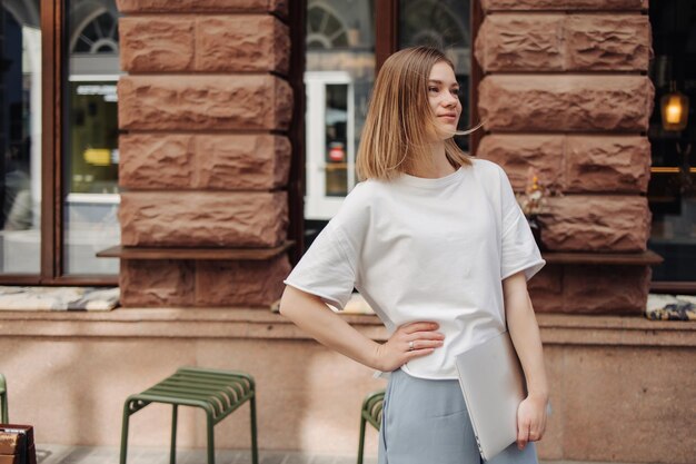 Caucasian woman look away on the street holding laptop