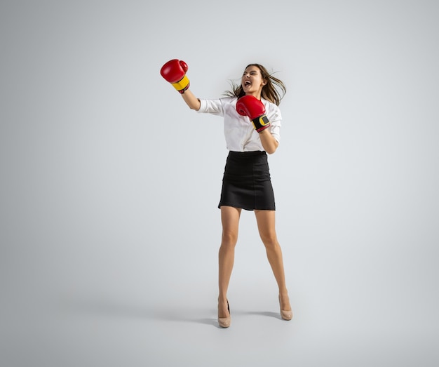 Caucasian woman in office clothes boxing on grey