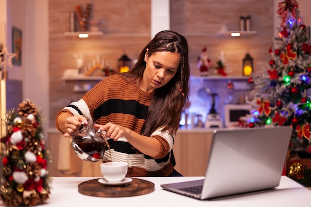 Caucasian woman pouring cup of tea from kettle