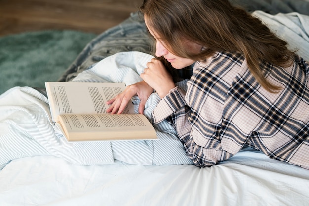 Free photo caucasian woman reading book in bed