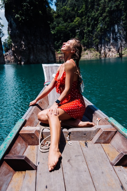休暇中のタイのアジアのボートに赤い夏のドレスを着た白人女性、タイを旅する