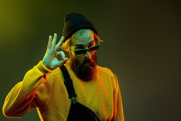 Caucasian woman's portrait on gradient studio background in neon light. Beautiful male model with hipster style in glasses. Concept of human emotions, facial expression, sales, ad. Showing nice.