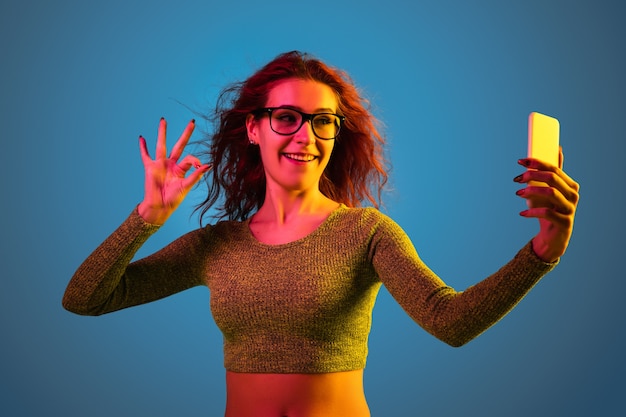 Free photo caucasian woman's portrait isolated on blue studio background in neon light.