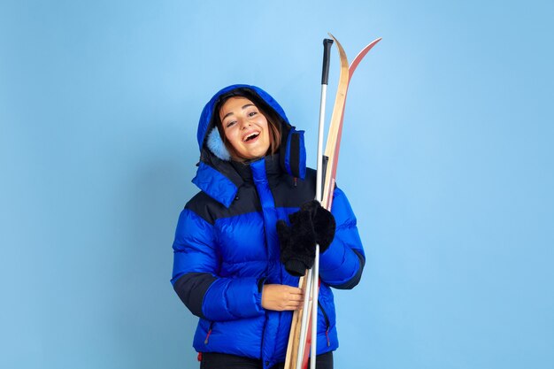 Caucasian woman's portrait isolated on blue studio background, winter theme