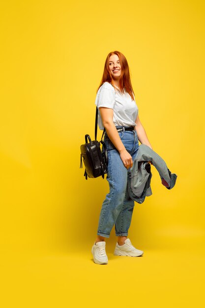 Caucasian woman's portrait on yellow background. Beautiful female red hair model.