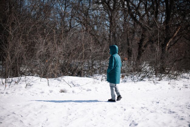 Caucasian woman stand on snowy road young woman in warm winter clothes walk through forest on frosty...