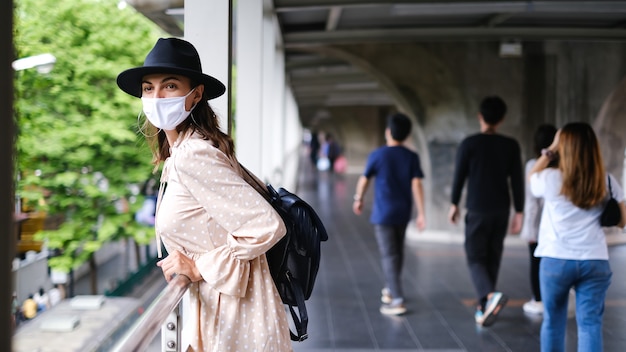 무료 사진 방콕 시내에서 유행병 동안 의료 얼굴 마스크에 지하철 교차점을 걷고 백인 여자.