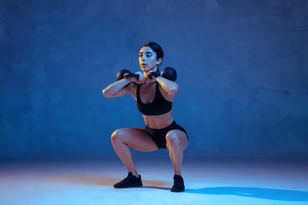네온 불빛에서 파란색으로 연습하는 백인 젊은 여성 운동선수
