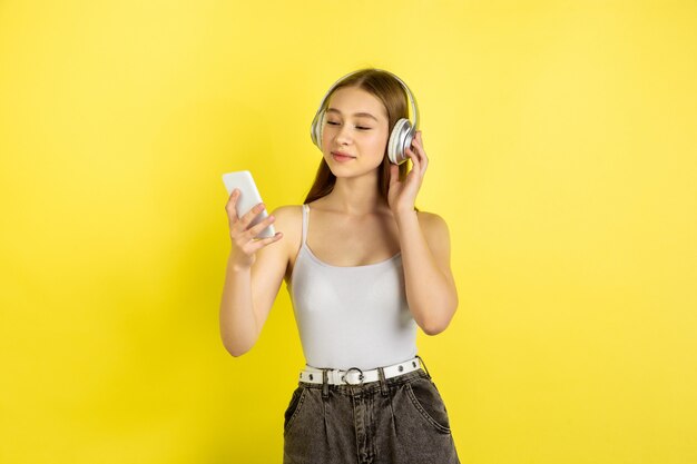 Caucasian young girl's portrait isolated on yellow studio