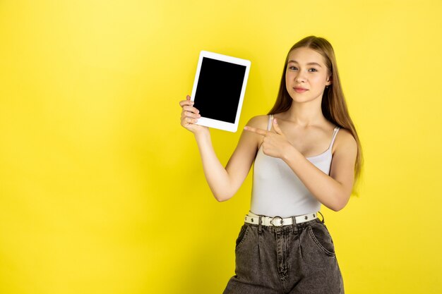 Caucasian young girl's portrait isolated on yellow studio