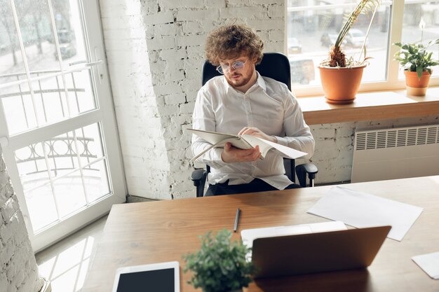 オンラインで勉強しているオフィスの仕事で働いているビジネス服装の白人の若い男